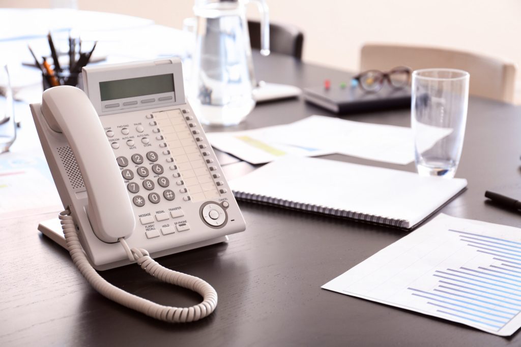 Table with telephone prepared for business meeting in conference hall